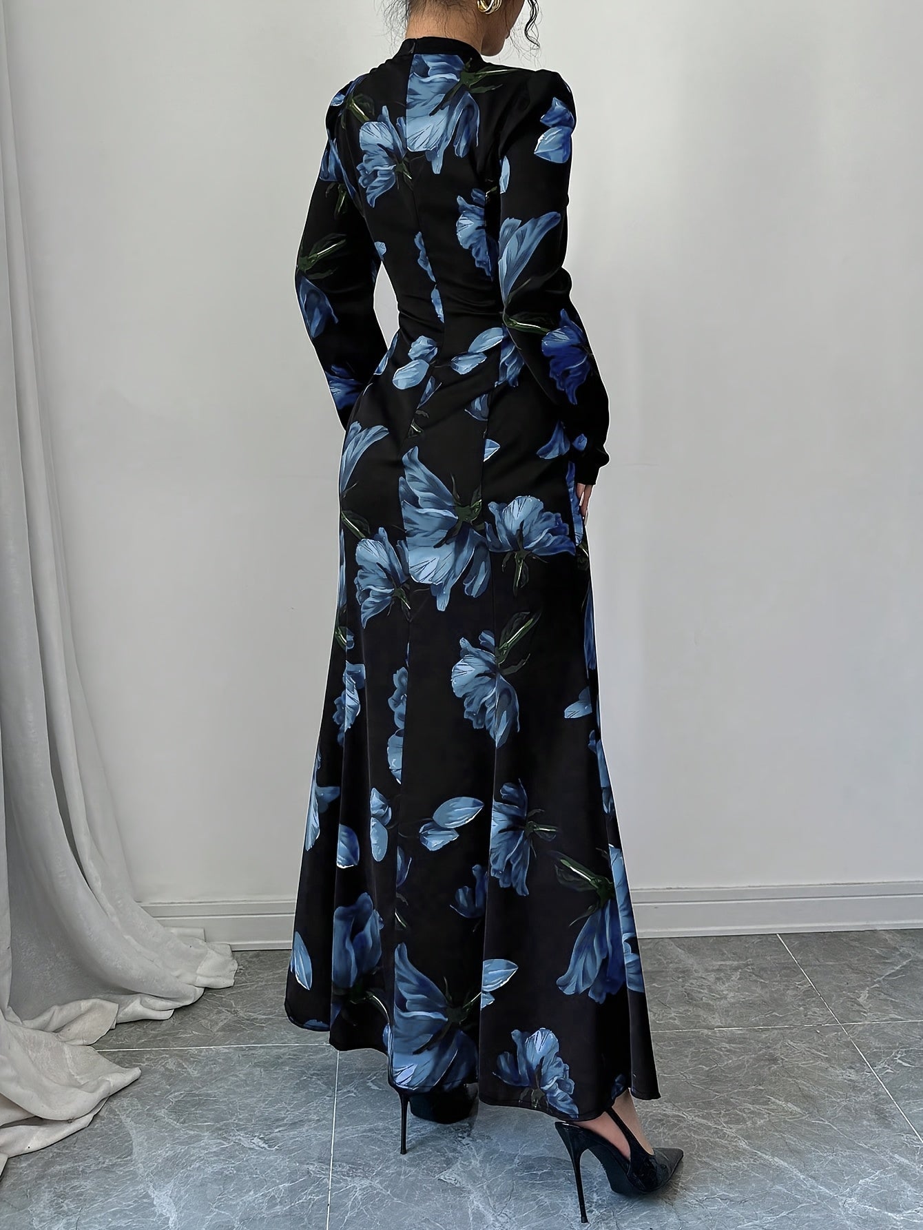 Robe maxi élégante à imprimé floral – manches longues, détail nœud au dos, taille cintrée, ourlet asymétrique, noire avec fleurs bleues, idéale automne/hiver, mode femme adulte, robe fleurie